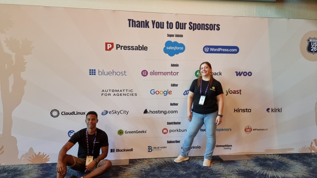 Alex and Ericka in front of the Sponsor board